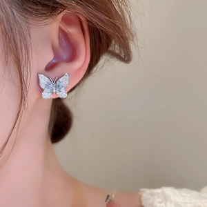 Close-up of a silver butterfly earring with gradient crystal detail on model's ear