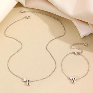 Détail du pendentif cœur et lettre R sur l'ensemble collier et bracelet argenté