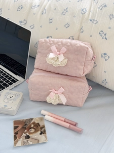 Detailed view of pink quilted cosmetic bags with heart patterns and lace bow details