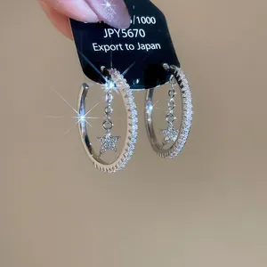 Macro view of C-shaped silver star hoop earrings with sparkling cubic zirconia pavé