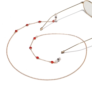 Detail of handmade gold eyeglass chain with red round crystals and silicone loops