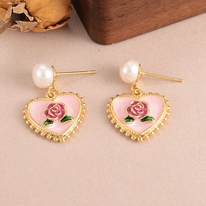 Detail of vintage heart earrings with pink enamel, rose floral pattern and white pearls