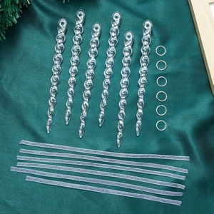 Close-up of 6 clear acrylic icicle ornaments with silver ribbons on green silk background