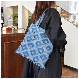 Detailed close-up of blue denim tote bag featuring frayed star patches and stitching