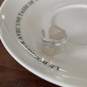 Detailed view of S925 sterling silver wide ring with irregular texture on ceramic dish