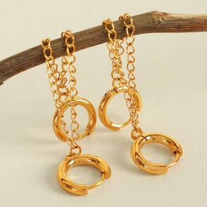Elegant gold chain drop earrings displayed on a branch with minimalist metal design