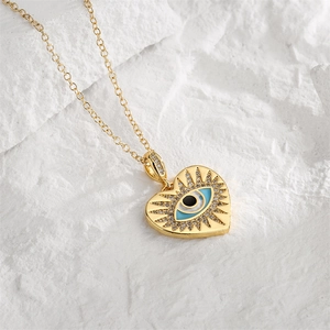 Gros plan détaillé du collier cœur doré avec œil maléfique bleu et pierres zircons