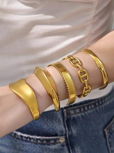 Detalle de pulseras y cadena de acero inoxidable chapado en oro 18k en primer plano