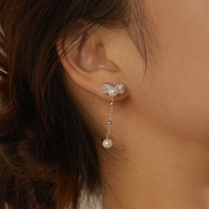 Close-up of elegant S925 silver bowknot earrings with pearls and zircon on model