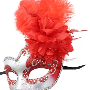 Dettaglio macro di piume rosse e paillettes floreali su una maschera veneziana da festa