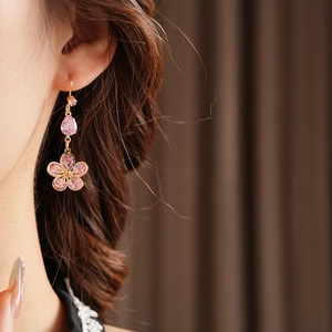 Detail of pink zircon flower earrings worn by a model in warm elegant lighting