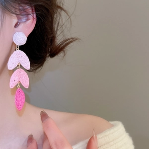 Detail of pink raffia fringe earrings with multi-layered crochet gradient flower petals