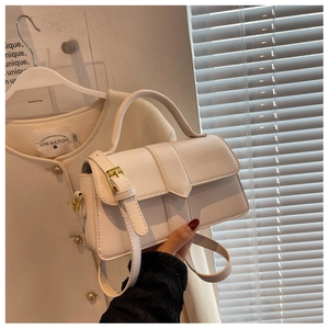 Detail of white rectangle crossbody bag with top handle and golden metal hardware