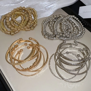Détail d'un ensemble de bracelets or et argent avec reliefs d'étoiles et perles élastiques