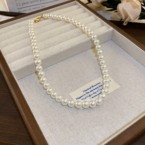 Detailed view of white pearls with a golden clasp on a beige velvet jewelry display