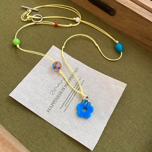 Detail of colorful beaded flower necklace with blue pendant and yellow woven cord