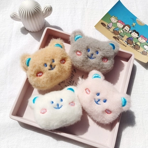 Detail of colorful plush bear brooches in khaki grey white and pink with embroidery