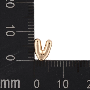 Macro shot of gold bubble letter V pendant showing size 8mm by 10mm on scale