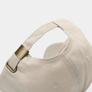 Vue détaillée d'une casquette en sergé beige avec boucle de réglage en métal bronzé