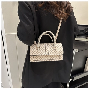 Detail view of stylish cream handbag with geometric pattern and golden metal hardware
