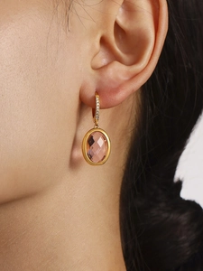 Detailed view of gold earrings with pink oval stone and micro-paved zircons on model