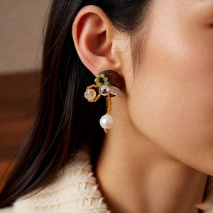 Detail eines Vintage-Ohrrings mit brauner Scheibe, Perlen und weißer Hängeperle am Model