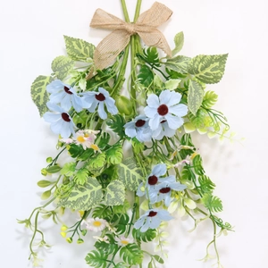 Artificial blue daisy flowers with burlap bow and green leaves for wall decoration