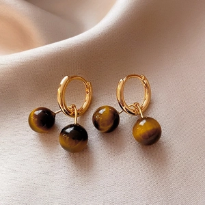 Close-up of vintage gold hoop earrings featuring tiger eye stone beads on satin.