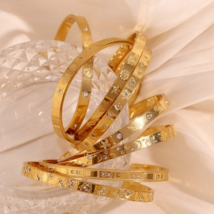 Detailed close-up of 18K gold plated bangles with ocean carvings and zircon inlays