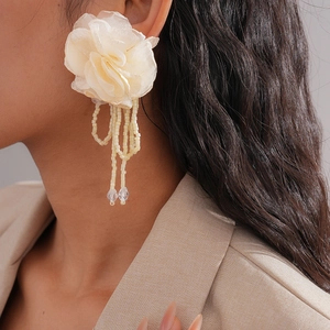 Detailed view of oversized ivory chiffon flower earrings with long beaded tassels