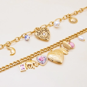 Detail of vintage gold layered bracelets with heart, elephant, and sun pendants