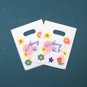 Detail view of a white plastic gift bag with colorful floral prints and Missing You text
