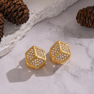 Golden cubic dice hoop earrings with crystal pavé setting on marble background