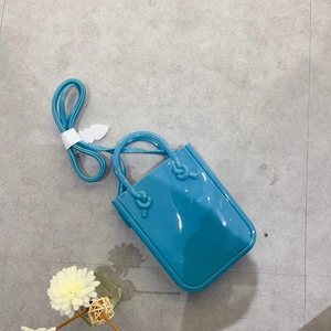 Blue jelly PVC phone handbag with shoulder strap and floral decor on grey tile