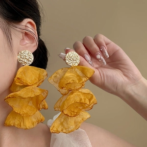 Detail of yellow layered chiffon petal earrings with textured golden metal studs