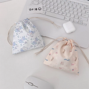 Close-up of cute cartoon bear and bunny drawstring pouches on a minimalist desk setup
