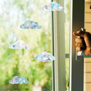 Rainbow prism static window clings in cloud shapes shown on a glass window with hands