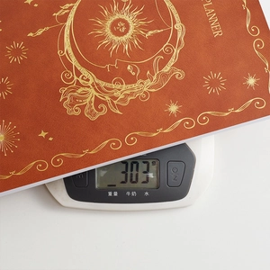 Burnt orange faux leather celestial planner with gold sun design weighing 303g