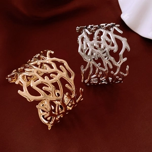 Close-up of gold and silver hollowed-out coral branch bangles on red velvet background