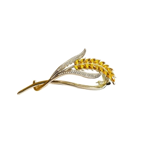 Elegant gold wheat-shaped hair clip with yellow crystal rhinestones on a white surface