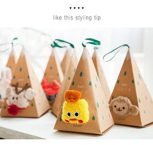 Detail of pyramid-shaped gift boxes featuring plush animal faces and green silk handles