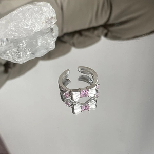 Macro shot of silver bow ring with pink zircon stones and adjustable open band design