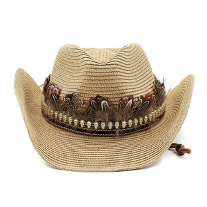 Detail of straw cowboy hat with silver skull beads and natural feather band decoration