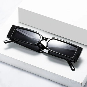 Retro rectangular sunglasses with black glossy frames and dark lenses on stone pedestal