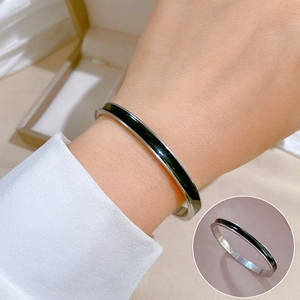 Detail of minimalist silver stainless steel cuff bracelet with black enamel inlay