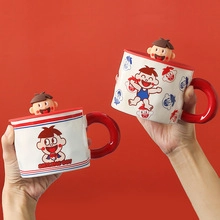Close-up of ceramic Christmas mugs with 3D cartoon character lids and red handles