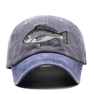 Detailed close-up of gray washed cotton baseball cap with blue brim and fish embroidery