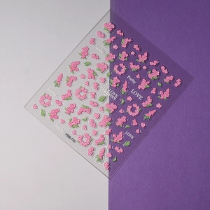 Macro detail of 5D embossed pink floral nail stickers with text and leaf patterns