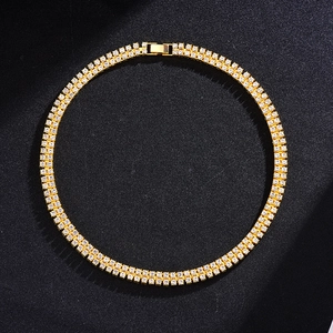 Close-up of golden double-row tennis chain with sparkling rhinestones on black background