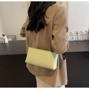 Detailed view of lime green leather baguette bag worn with a chic camel blazer